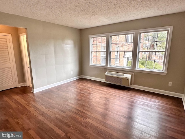 spare room featuring plenty of natural light, dark hardwood / wood-style floors, a wall mounted AC, and a textured ceiling