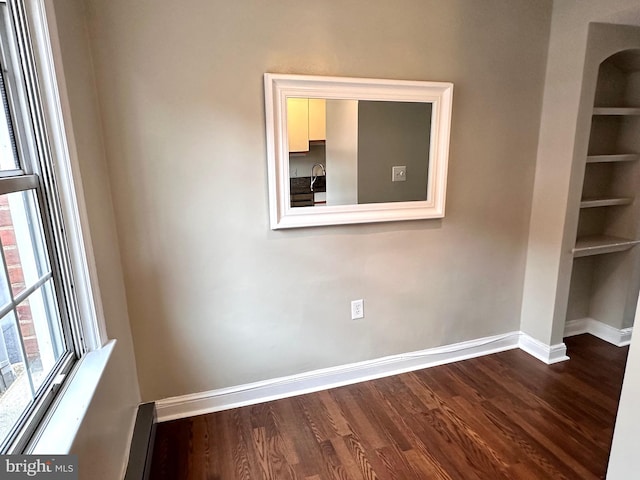 empty room with hardwood / wood-style flooring and built in features