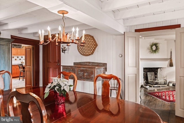 dining room with wood walls, an inviting chandelier, a fireplace, beam ceiling, and dark hardwood / wood-style flooring