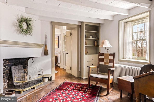 living area featuring beamed ceiling, radiator heating unit, and hardwood / wood-style flooring