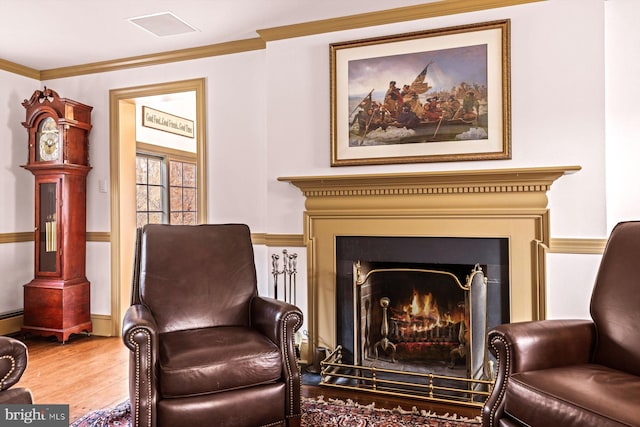 sitting room with hardwood / wood-style floors, ornamental molding, and baseboard heating