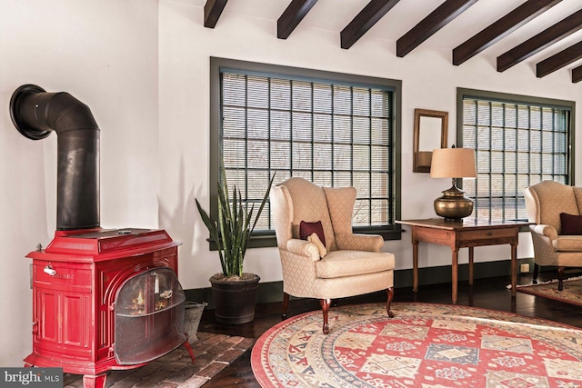 sitting room featuring beam ceiling and a wood stove