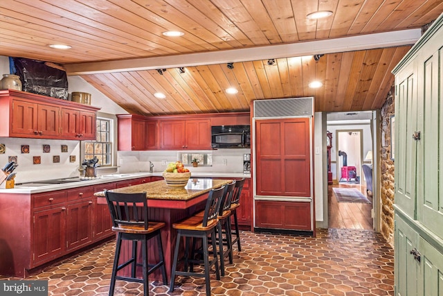 kitchen featuring a center island, wooden ceiling, paneled refrigerator, cooktop, and lofted ceiling with beams