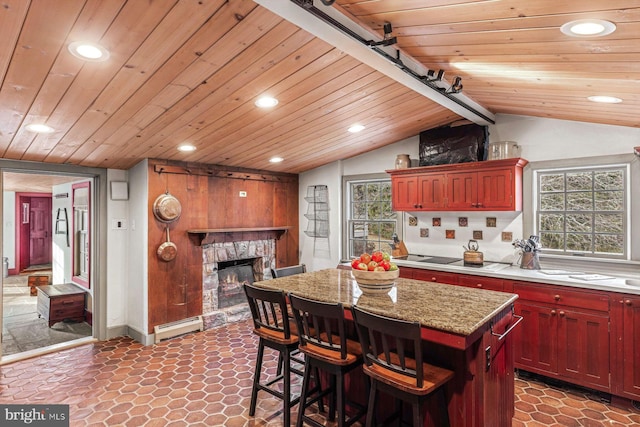 kitchen with a center island, wooden ceiling, a baseboard radiator, lofted ceiling with beams, and a fireplace