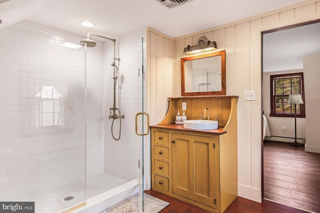 bathroom with baseboard heating, vanity, a shower with shower door, and hardwood / wood-style flooring