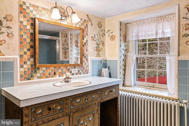 bathroom with vanity, radiator, and tile walls