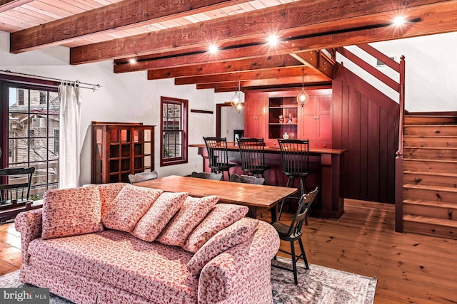 living room featuring wood walls, beamed ceiling, wooden ceiling, and light wood-type flooring