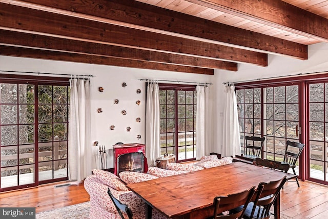 dining room with beamed ceiling, a healthy amount of sunlight, light hardwood / wood-style floors, and wooden ceiling