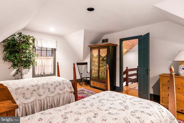 bedroom with light wood-type flooring and lofted ceiling