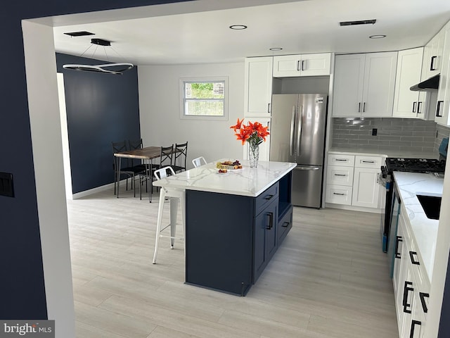 kitchen with tasteful backsplash, stainless steel appliances, a kitchen island, pendant lighting, and white cabinetry