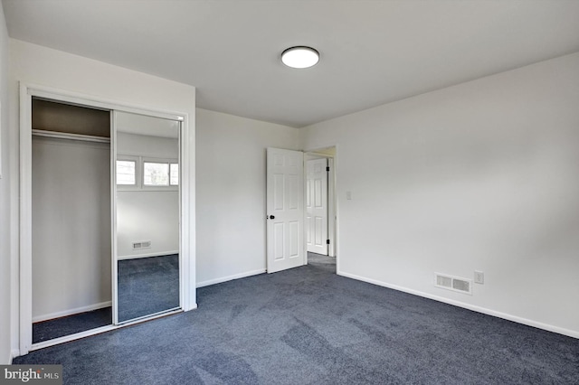 unfurnished bedroom featuring dark carpet and a closet