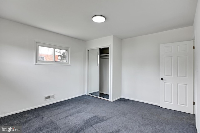 unfurnished bedroom with a closet and dark carpet