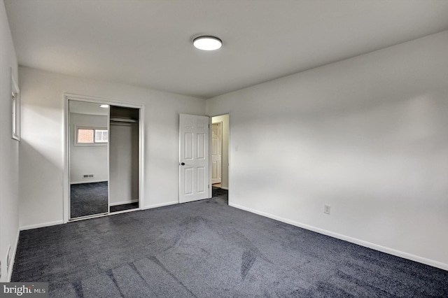 unfurnished bedroom with dark colored carpet and a closet