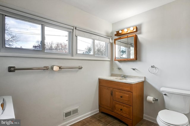 bathroom featuring plenty of natural light, toilet, and vanity