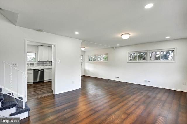 unfurnished living room featuring dark hardwood / wood-style flooring and a wealth of natural light