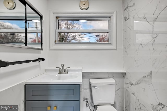 bathroom featuring vanity, toilet, and tile walls