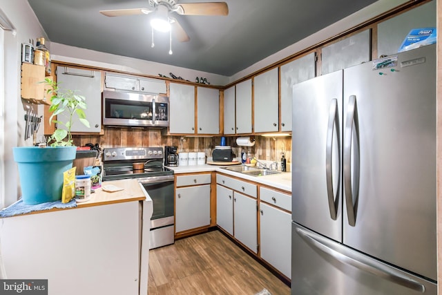 kitchen featuring ceiling fan, sink, dark wood-type flooring, stainless steel appliances, and backsplash