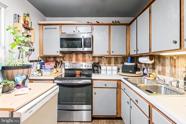 kitchen featuring white cabinets, sink, light wood-type flooring, appliances with stainless steel finishes, and tasteful backsplash