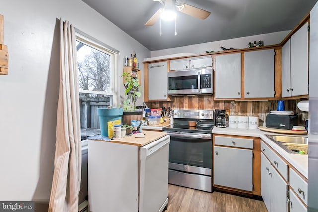 kitchen with sink, ceiling fan, light wood-type flooring, appliances with stainless steel finishes, and white cabinetry