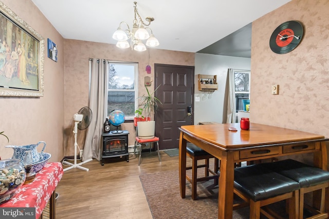 dining room featuring a wood stove, an inviting chandelier, and hardwood / wood-style flooring