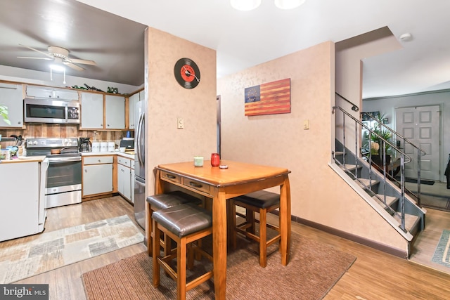 kitchen featuring light wood-type flooring, tasteful backsplash, stainless steel appliances, ceiling fan, and white cabinetry