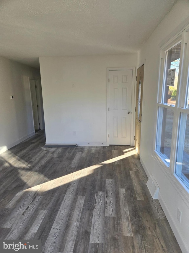 unfurnished room with a textured ceiling and dark wood-type flooring