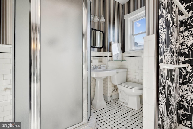 bathroom featuring tile patterned floors, toilet, tile walls, and walk in shower