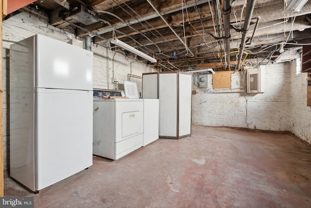 basement with electric panel, washer and clothes dryer, and white refrigerator