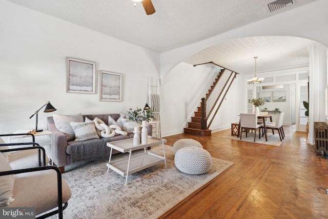 living room featuring radiator heating unit and ceiling fan with notable chandelier