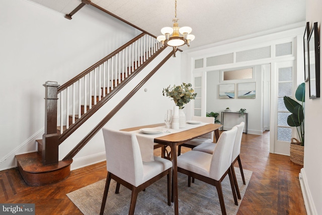 dining space with dark parquet flooring and a chandelier