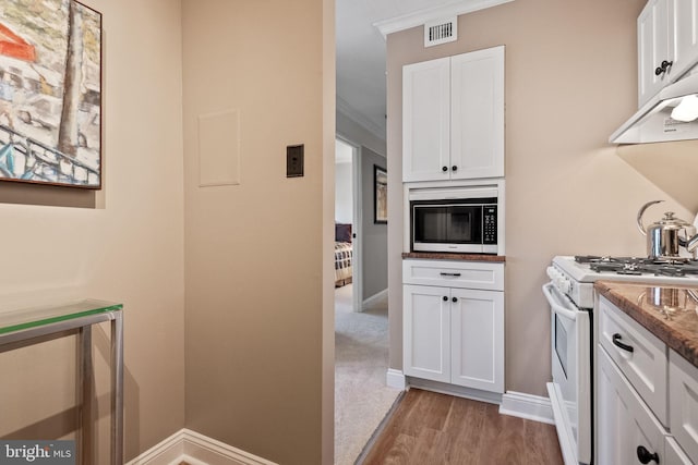 kitchen with white range with gas stovetop, ornamental molding, stone countertops, white cabinets, and light wood-type flooring