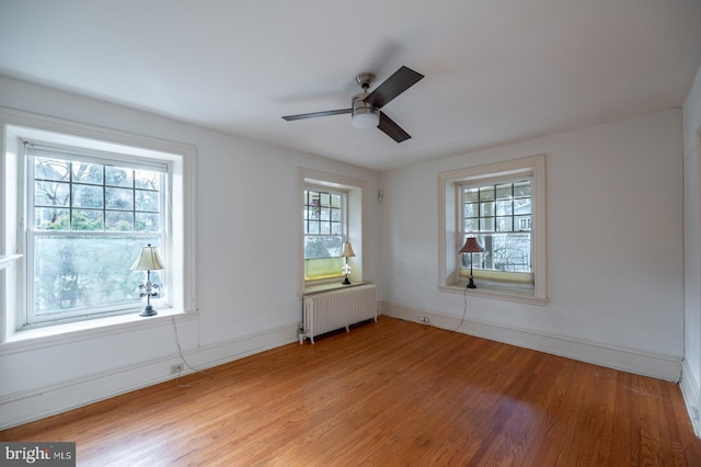 spare room featuring a wealth of natural light, radiator heating unit, ceiling fan, and light hardwood / wood-style flooring