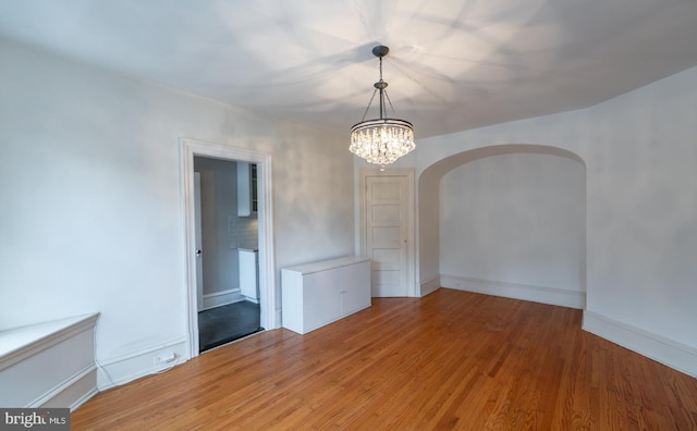 spare room featuring wood-type flooring and a notable chandelier