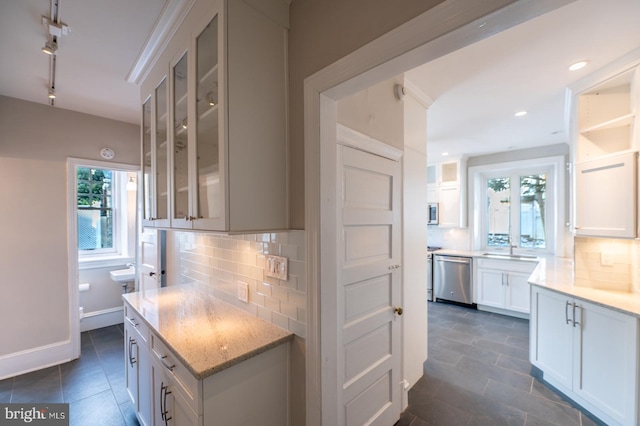 kitchen with dishwasher, sink, tasteful backsplash, light stone counters, and white cabinets