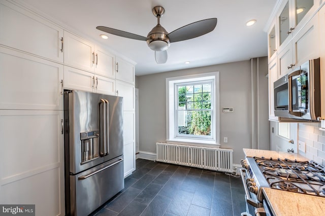 kitchen with backsplash, radiator, ceiling fan, high quality appliances, and white cabinetry