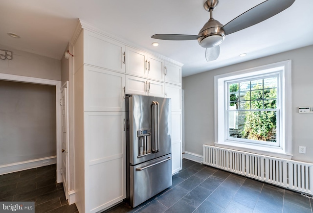 kitchen featuring high quality fridge, ceiling fan, radiator heating unit, and white cabinets