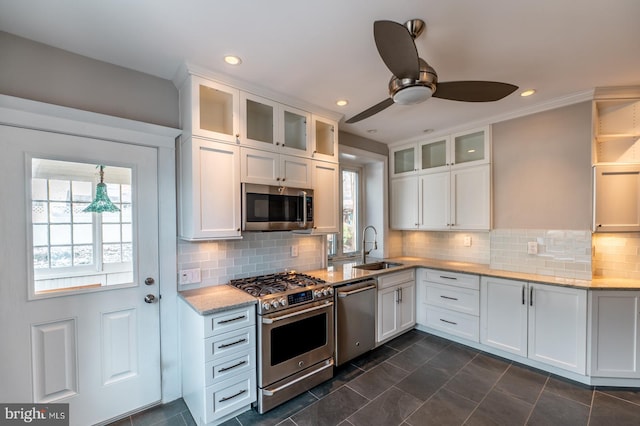 kitchen with white cabinets, stainless steel appliances, light stone counters, and sink