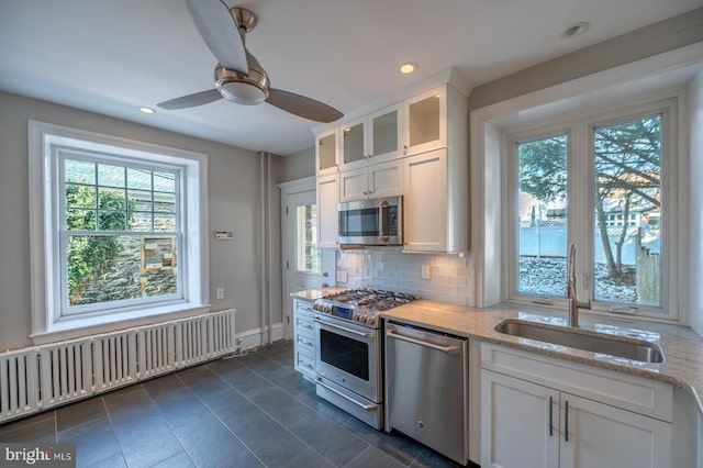 kitchen with white cabinets, decorative backsplash, stainless steel appliances, and sink