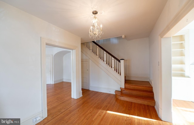 staircase with a notable chandelier and wood-type flooring