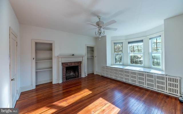 unfurnished living room featuring a fireplace, ceiling fan, dark wood-type flooring, and radiator