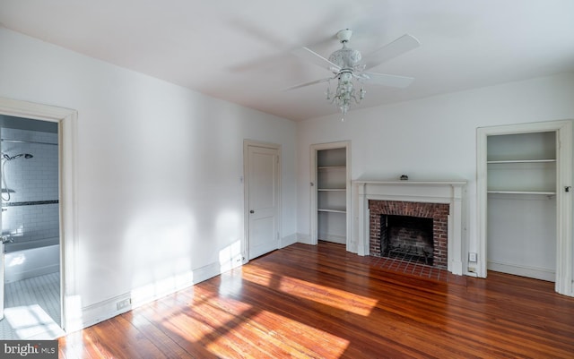 unfurnished living room featuring ceiling fan, a fireplace, and dark wood-type flooring