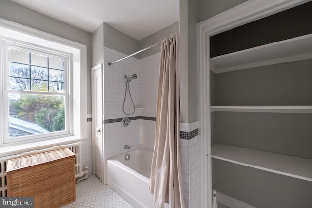 bathroom featuring shower / bath combo with shower curtain and radiator