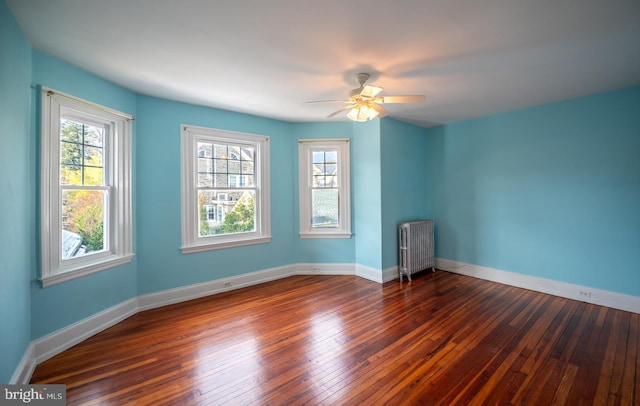 spare room featuring dark hardwood / wood-style floors, radiator, and ceiling fan