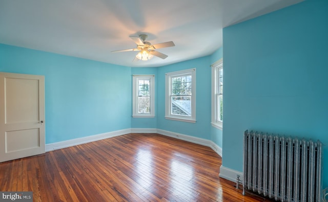 empty room featuring hardwood / wood-style floors, radiator, and ceiling fan