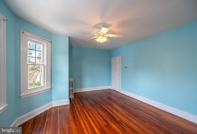 unfurnished room featuring radiator heating unit, ceiling fan, and dark wood-type flooring