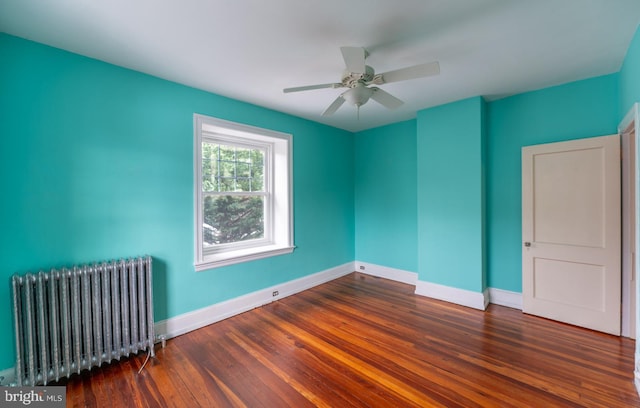 empty room with dark hardwood / wood-style floors, radiator, and ceiling fan