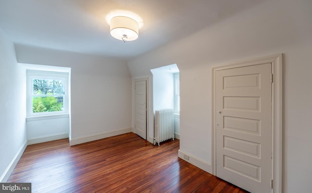 spare room featuring dark hardwood / wood-style flooring and radiator heating unit