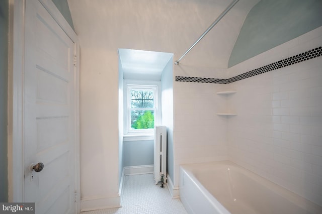 bathroom featuring tiled shower / bath, radiator, and vaulted ceiling