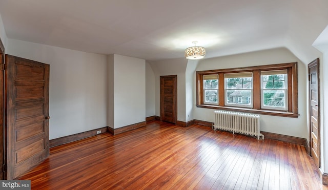 additional living space featuring dark hardwood / wood-style flooring, radiator, and lofted ceiling