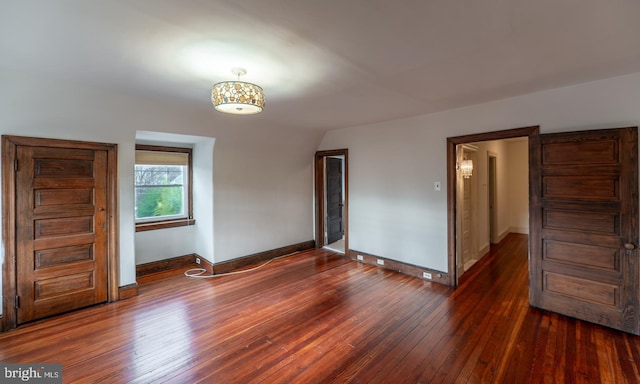 spare room featuring dark hardwood / wood-style flooring and lofted ceiling